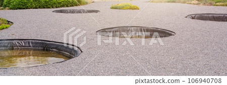 Containers for watering plants in the garden. Artificial small pools in the garden for collecting rainwater and watering plants. 106940708