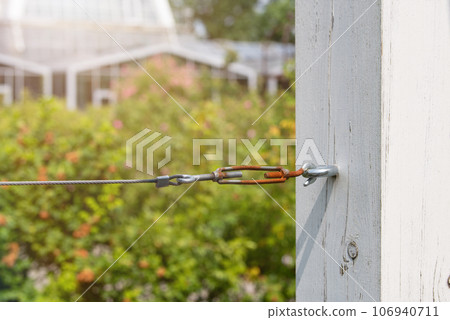 Close-up of a cable tensioner in a park. Fun concept with zip line. To be inserted into a design or project. Close-up of a cable tensioner in a park. Fun concept with zip line. To be inserted into a design or project. 106940711