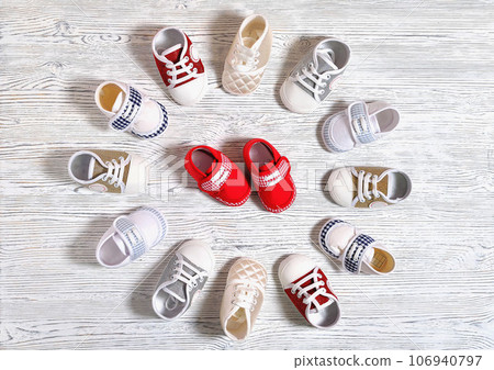 multi-colored children's shoes on a white-gray non-uniform wooden background close-up 106940797