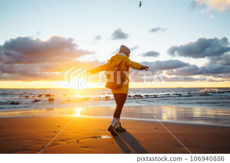 Tourist in yellow jacket enjoying sea landscape at sunset. Lifestyle, travel, nature, active life. Tourist in yellow jacket enjoying sea landscape at sunset. Lifestyle, travel, nature, active life. 106940886