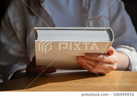 Hand holding new closed book for reading Hand holding new closed book for reading 106940958