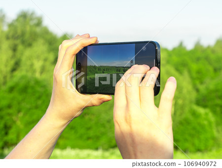 Hands holding mobile phone, taking photo of nature Hands holding mobile phone, taking photo of nature 106940972