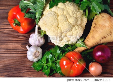 Vegetables cauliflower, bell pepper, parsnip, onion, garlic, parsley on a wooden background 106941092
