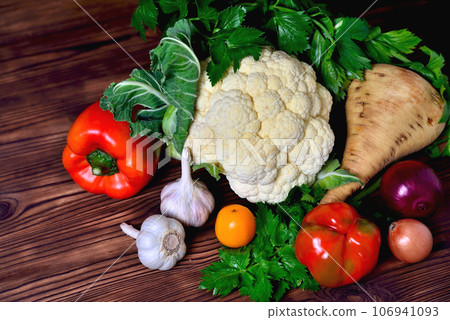 Vegetables cauliflower, bell pepper, parsnip, onion, garlic, parsley on a wooden background Vegetables cauliflower, bell pepper, parsnip, onion, garlic, parsley on a wooden background 106941093