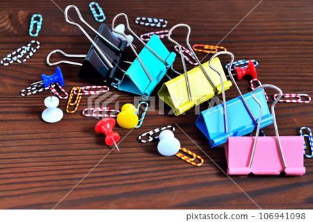 Buttons, colored paper clips, paper clips on a natural brown background 106941098