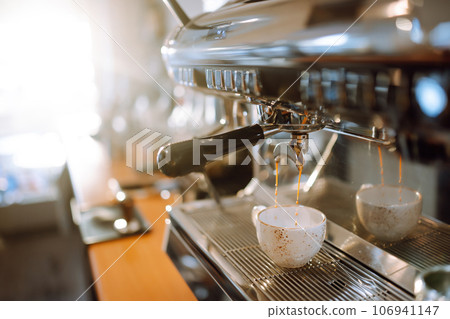 Hot delicious coffee pouring from coffee machine into coffee cup. Hot delicious coffee pouring from coffee machine into coffee cup. 106941147
