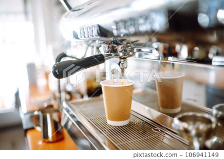 Hot delicious coffee pouring from coffee machine into coffee cup. Hot delicious coffee pouring from coffee machine into coffee cup. 106941149