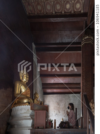 Young woman sitting pay respect to Phra Phuttha Chinnarat in the chapel at Wat yai suwannaram temple. 106941185