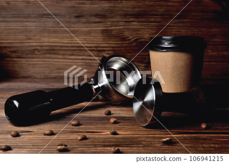 temper portafilter coffee beans cardboard coffee cup on a brown wooden background close-up copy space temper portafilter coffee beans cardboard coffee cup on a brown wooden background close-up copy space 106941215