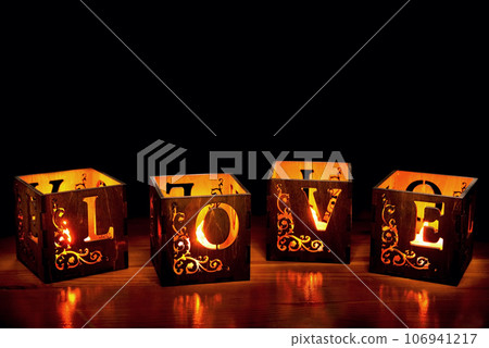 Wooden candlesticks with lighted candles on a dark background Wooden candlesticks with lighted candles on a dark background 106941217