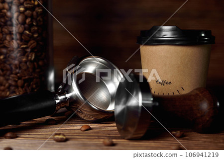 temper portafilter coffee beans cardboard coffee cup on a brown wooden background close-up copy space temper portafilter coffee beans cardboard coffee cup on a brown wooden background close-up copy space 106941219