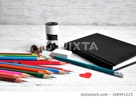 Pencils, notepad, sharpener, eraser and shavings from pencils on a gray non-uniform background 106941225