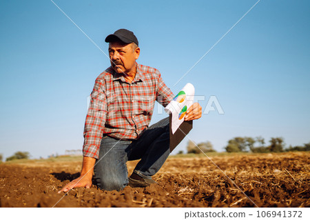 Male hands touching soil on the field. Expert hand of farmer checking soil health. Ecology concept. Male hands touching soil on the field. Expert hand of farmer checking soil health. Ecology concept. 106941372