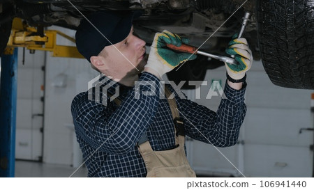 An auto mechanic repairs a car's suspension. Car suspension repair 106941440