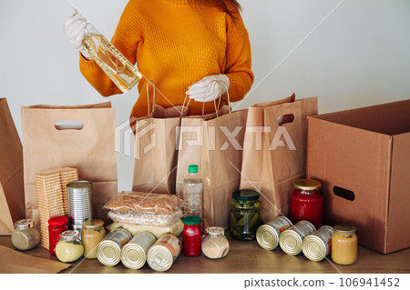 woman in medical gloves packing food for donation 106941452