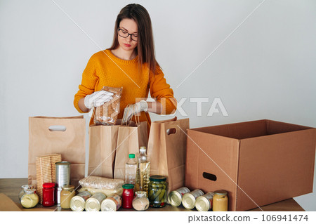 woman in medical gloves packing food for donation 106941474