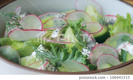 Healthy organic food. The cook prepares a salad with cucumber and radish, the cook prepares a light salad, vegetarian food, a handsome caucasian male cook presents a delicious dish, close-up. 106941515