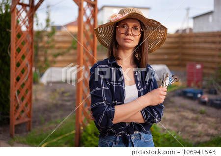 Portrait woman gardener in hat working in the garden in the backyard Portrait woman gardener in hat working in the garden in the backyard 106941543