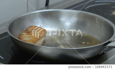 A young chef cooks in the restaurant kitchen, the cook fries meat in the kitchen, the cafe kitchen and the cook at the stove cooks. Close-up. A young chef cooks in the restaurant kitchen, the cook fries meat in the kitchen, the cafe kitchen and the cook at the stove cooks. Close-up. 106941571