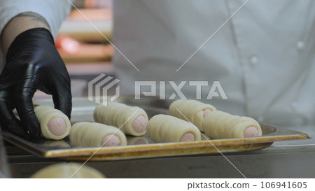 The cook prepares sausages in the dough, the baker makes sausages in the dough, the chef prepares hot dogs The cook prepares sausages in the dough, the baker makes sausages in the dough, the chef prepares hot dogs 106941605