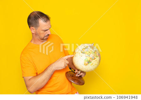 Happy brunette Hispanic man 40 years old, wears orange t-shirt, holds in hands Earth point, world globe, isolated on plain orange background. Stop natural garbage ecology protection concept. Happy brunette Hispanic man 40 years old, wears orange t-shirt, holds in hands Earth point, world globe, isolated on plain orange background. Stop natural garbage ecology protection concept. 106941948