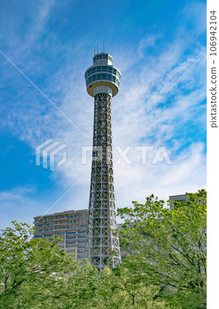 White Yokohama Marine Tower above the fresh green seasonal trees 106942104