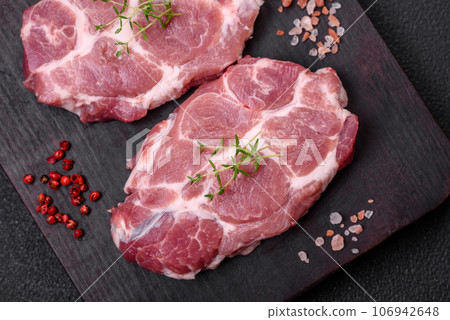 Fresh juicy pork steaks with salt, spices and herbs 106942648