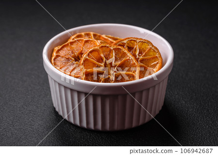 Dried round slices of tangerine, orange or lemon on a dark concrete background Dried round slices of tangerine, orange or lemon on a dark concrete background 106942687