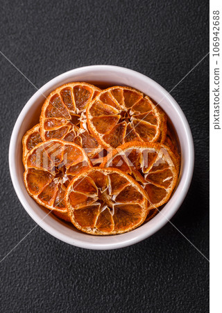 Dried round slices of tangerine, orange or lemon on a dark concrete background Dried round slices of tangerine, orange or lemon on a dark concrete background 106942688