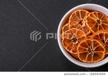 Dried round slices of tangerine, orange or lemon on a dark concrete background Dried round slices of tangerine, orange or lemon on a dark concrete background 106942689