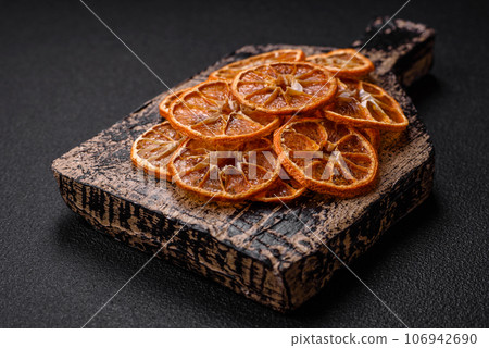 Dried round slices of tangerine, orange or lemon on a dark concrete background Dried round slices of tangerine, orange or lemon on a dark concrete background 106942690