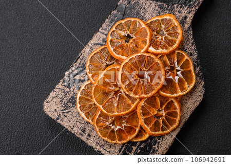 Dried round slices of tangerine, orange or lemon on a dark concrete background Dried round slices of tangerine, orange or lemon on a dark concrete background 106942691