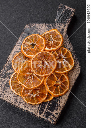 Dried round slices of tangerine, orange or lemon on a dark concrete background 106942692