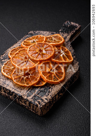 Dried round slices of tangerine, orange or lemon on a dark concrete background Dried round slices of tangerine, orange or lemon on a dark concrete background 106942693