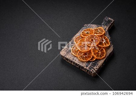 Dried round slices of tangerine, orange or lemon on a dark concrete background Dried round slices of tangerine, orange or lemon on a dark concrete background 106942694