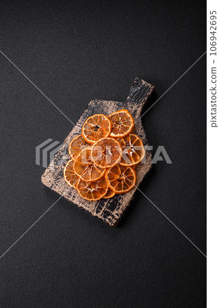 Dried round slices of tangerine, orange or lemon on a dark concrete background Dried round slices of tangerine, orange or lemon on a dark concrete background 106942695