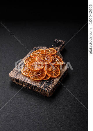 Dried round slices of tangerine, orange or lemon on a dark concrete background Dried round slices of tangerine, orange or lemon on a dark concrete background 106942696
