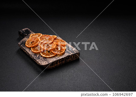 Dried round slices of tangerine, orange or lemon on a dark concrete background Dried round slices of tangerine, orange or lemon on a dark concrete background 106942697