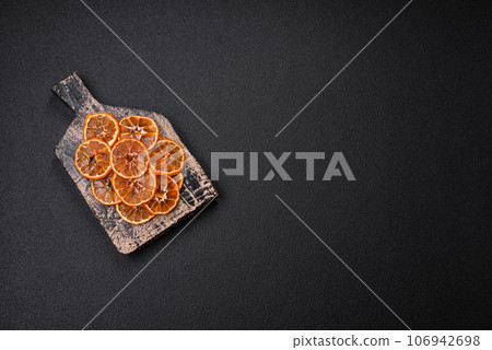 Dried round slices of tangerine, orange or lemon on a dark concrete background Dried round slices of tangerine, orange or lemon on a dark concrete background 106942698
