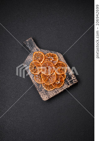 Dried round slices of tangerine, orange or lemon on a dark concrete background Dried round slices of tangerine, orange or lemon on a dark concrete background 106942699
