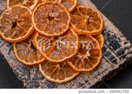 Dried round slices of tangerine, orange or lemon on a dark concrete background Dried round slices of tangerine, orange or lemon on a dark concrete background 106942700