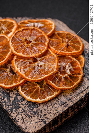 Dried round slices of tangerine, orange or lemon on a dark concrete background Dried round slices of tangerine, orange or lemon on a dark concrete background 106942701