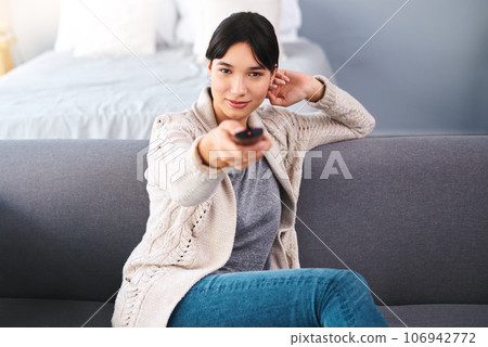 Watching tv, portrait of happy woman with remote and in bedroom of their home. Entertainment or comfortable relaxation, news or television and cheerful female person streaming movie or series 106942772