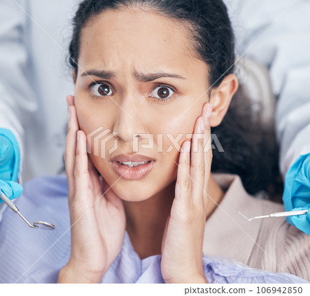 Trips to the dentists can be a nightmare. Shot of a young woman looking afraid at her dentists office. 106942850