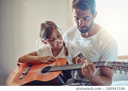 Father with daughter, guitar with teaching and learning at home, bonding with love and creativity. Family, man and girl learn to play musical instrument, lesson and music education with talent 106943166