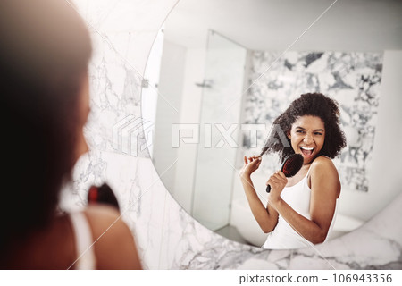 Woman, beauty and singing in mirror at apartment for haircare, fun, and preparing for the day. Female glow, happy and skincare with singer in the mirror for morning routine with hair and happiness. 106943356