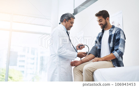 Healthcare, patient and doctor with blood pressure test, help and wellness checkup of person at hospital. Medicine, health care expert and Indian man in doctors office consulting medical professional 106943453