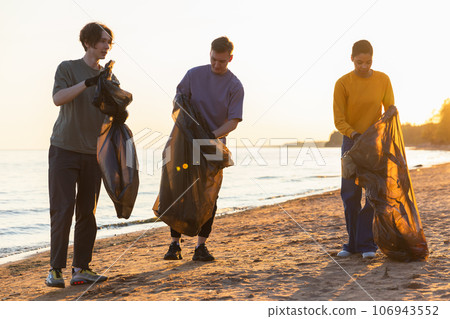 Earth day. Volunteers activists team collects garbage cleaning of beach coastal zone. Woman mans with trash in garbage bag on ocean shore. Environmental conservation coastal zone cleaning Earth day. Volunteers activists team collects garbage cleaning of beach coastal zone. Woman mans with trash in garbage bag on ocean shore. Environmental conservation coastal zone cleaning 106943552