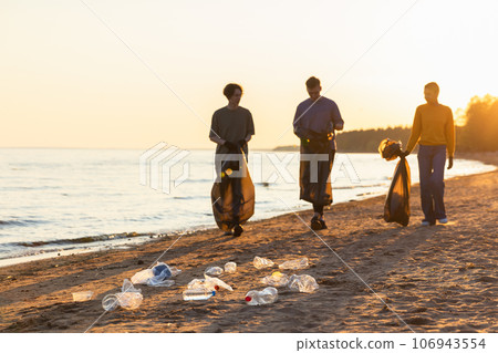 Earth day. Volunteers activists team collects garbage cleaning of beach coastal zone. Woman mans with trash in garbage bag on ocean shore. Environmental conservation coastal zone cleaning Earth day. Volunteers activists team collects garbage cleaning of beach coastal zone. Woman mans with trash in garbage bag on ocean shore. Environmental conservation coastal zone cleaning 106943554