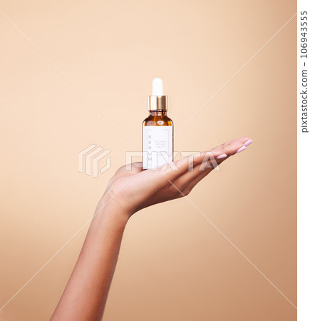 Hand, product and antiaging serum with a woman in studio on a beige background to promote skincare. Marketing, advertising and luxury with a female holding a bottle for the promotion of beauty Hand, product and antiaging serum with a woman in studio on a beige background to promote skincare. Marketing, advertising and luxury with a female holding a bottle for the promotion of beauty 106943555